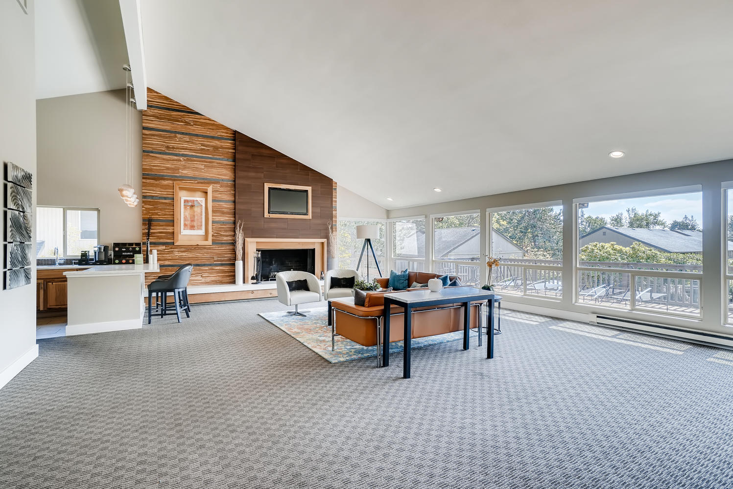 Clubhouse lounge with sofas around a fireplace and large open windows