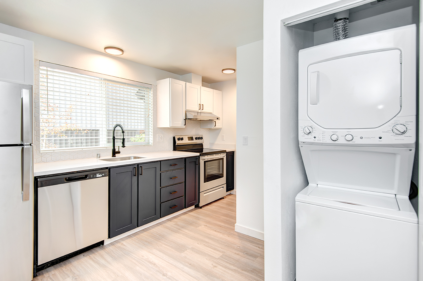 Slight view of stackable washer dryer and kitchen