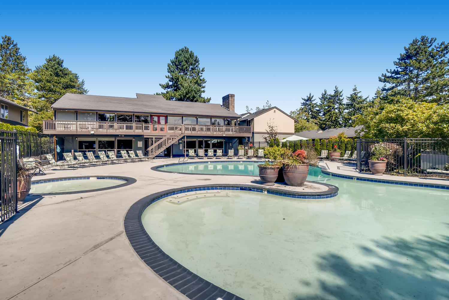 fenced pool deck with deck seating and umbrellas