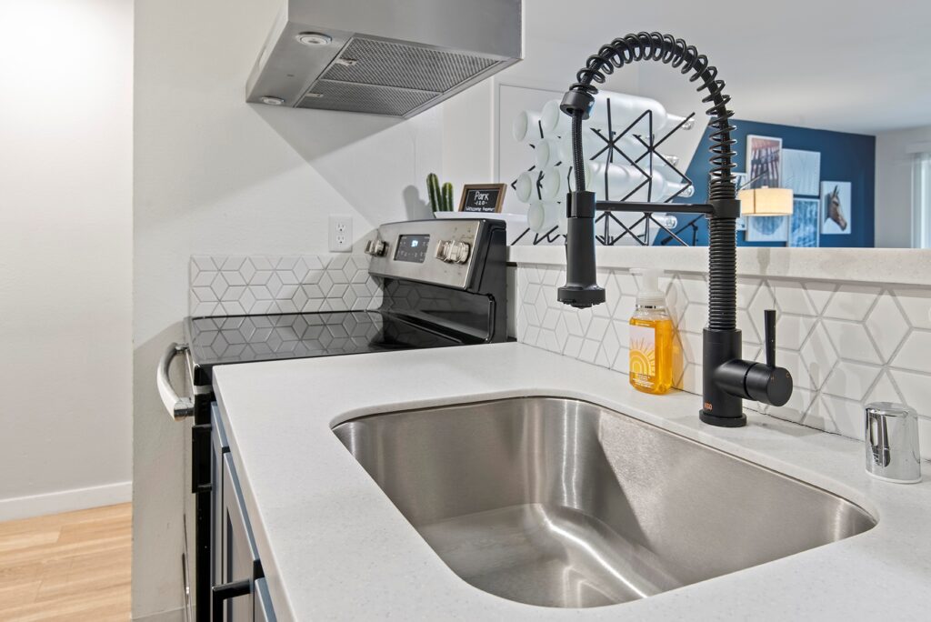 Kitchen sink with a nice white backsplash and a stove